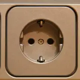 Gniazdko elektryczne w kolorze brązowym. Dowiedz się, jak przenieść gniazdko bez kucia, stosując proste rozwiązania.