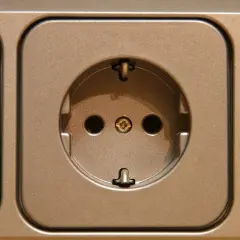 Gniazdko elektryczne w kolorze brązowym. Dowiedz się, jak przenieść gniazdko bez kucia, stosując proste rozwiązania.
