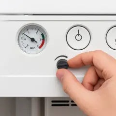Dolewanie wody do CO. Ręka kręci pokrętłem, manometr wskazuje niskie ciśnienie.