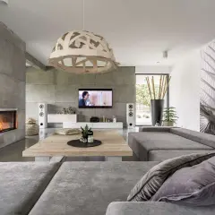 Nowoczesny salon z dominującym betonem w architekturze. Kominek, ściany i podłoga tworzą surową bazę dla przytulnych mebli.