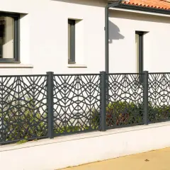 Nowoczesne, ciekawe ogrodzenia posesji z metalowymi panelami o geometrycznym wzorze liści. Elegancko oddzielają dom od ulicy.