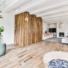 Nowoczesny salon z drewnianą ścianką i podłogą. Płytki drewnopodobne w salonie aranżacje tworzą ciepły klimat.