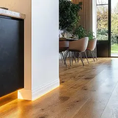 Nowoczesna listwa przypodłogowa z podświetleniem LED przy drewnianej podłodze.
