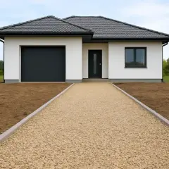 Nowy dom z garażem i wejściem, do którego prowadzi żwirowy podjazd do domu.