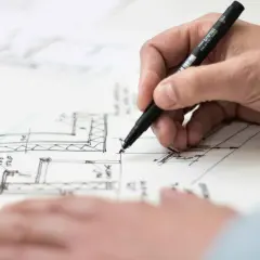 Rysowanie dokumentów do budowy domu krok po kroku. Dłoń trzyma pisak, tworząc szczegółowy plan.
