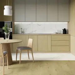 Nowoczesna kuchnia z drewnianymi frontami i eleganckim marmurem w tle. Okrągły stół i krzesła zapraszają do wspólnych posiłków.