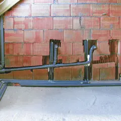 Instalacja hydrauliczna w trakcie budowy. Rury odpływowe i piony kanalizacyjne przygotowane do podłączenia, co jest kluczowe, by wiedzieć jak zrobić odpowietrzenie WC.