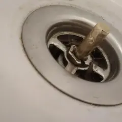 Korek do wanny z pokrętłem, widoczny mechanizm i włosy, wymaga naprawy.