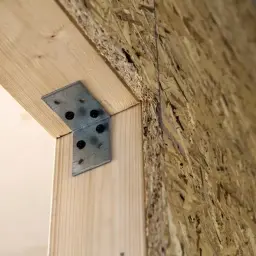 Metalowy kątownik wzmacnia połączenie drewna z płytą OSB. Tynk na OSB będzie kolejnym etapem budowy.
