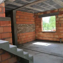 Trwa przekształcenie budynku gospodarczego na mieszkalny. Widać schody, ściany z pustaków ceramicznych i betonowy strop.