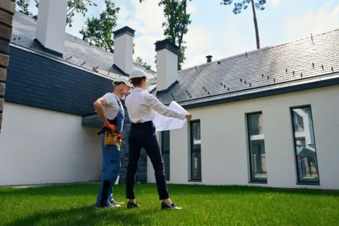 Architekt i budowlaniec omawiają plany domu. Czy można mieszkać w domu bez odbioru? To pytanie, na które odpowiedź znajdą na tym etapie budowy.