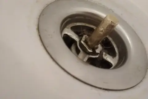 Korek do wanny z pokrętłem, widoczny mechanizm i włosy, wymaga naprawy.