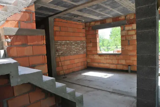 Trwa przekształcenie budynku gospodarczego na mieszkalny. Widać schody, ściany z pustaków ceramicznych i betonowy strop.