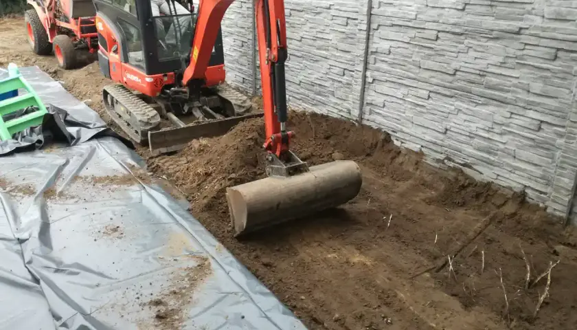 Koparka pracuje nad przygotowaniem terenu pod budowę, usuwając ziemię i przygotowując podłoże.