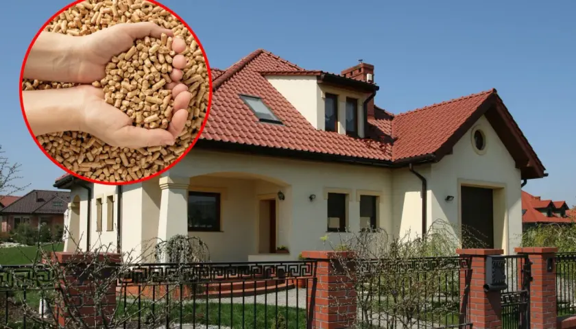 Domy z czerwonym dachem, w zbliżeniu dłonie trzymające pellet drzewny – ekologiczne i najtańsze ogrzewanie domu.