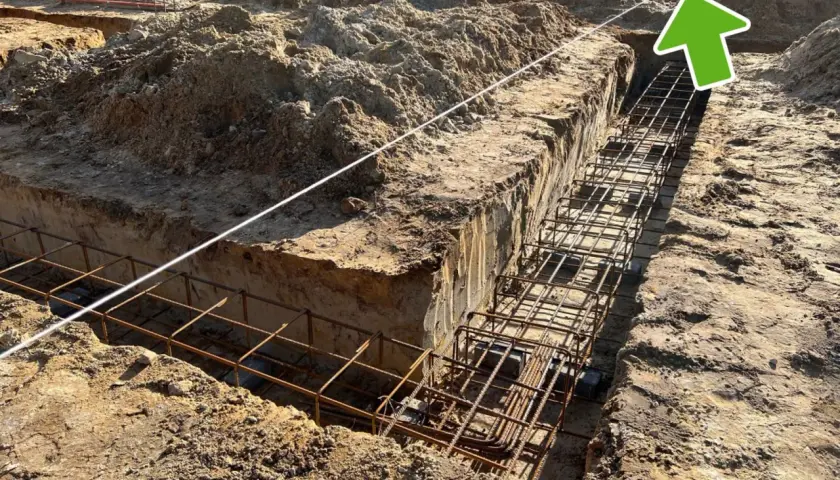 Sznurek budowlany pokazuje, jak wyznaczyć poziom fundamentów. W wykopie widać zbrojenie.