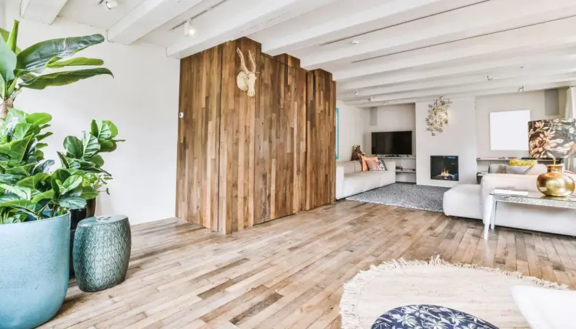 Nowoczesny salon z drewnianą ścianką i podłogą. Płytki drewnopodobne w salonie aranżacje tworzą ciepły klimat.