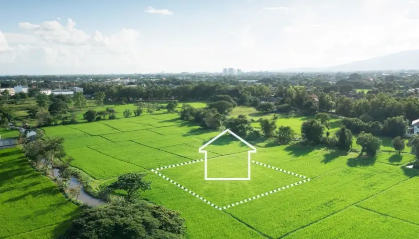 Zielona działka z obrysem domu, symbolizująca potencjalną inwestycję i podatek od sprzedaży działki.