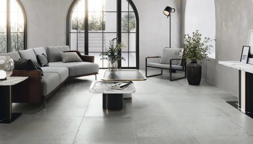 Nowoczesny salon z szarymi płytkami pod ogrzewanie podłogowe, wygodną sofą i designerskimi meblami.