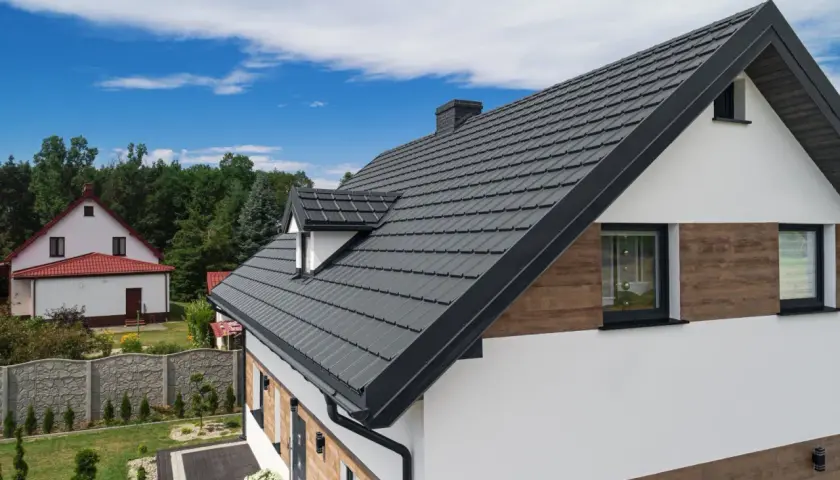 Nowoczesny dom z dachem pokrytym ciemnoszarą blachą. Elewacja łącząca biel z drewnopodobnymi panelami.