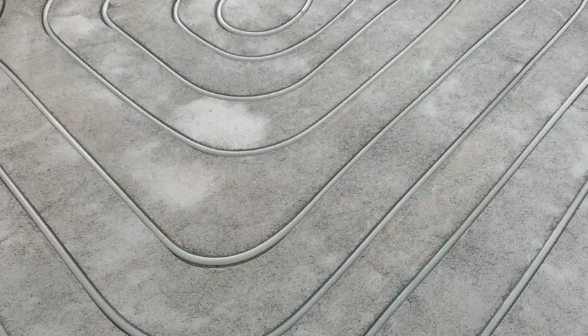 Wykonane frezowanie pod ogrzewanie podłogowe. Rury ułożone w betonowej posadzce tworzą spiralny wzór, gotowe do zalania.
