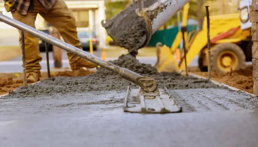 Betonowanie trwa, mimo że temperatura może być wyzwaniem. Robotnik wyrównuje świeży beton, który właśnie wylano z betoniarki.