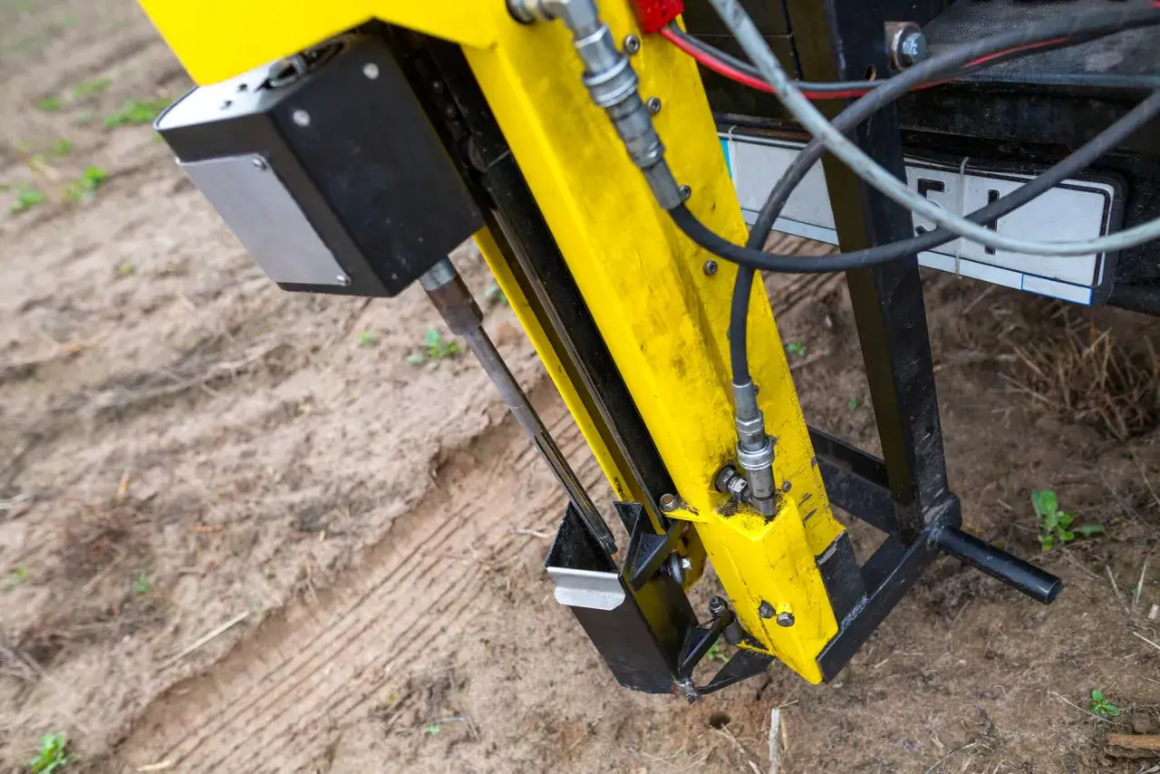 Żółta maszyna wykonuje badania geotechniczne gruntu, zagłębiając się w ziemię.