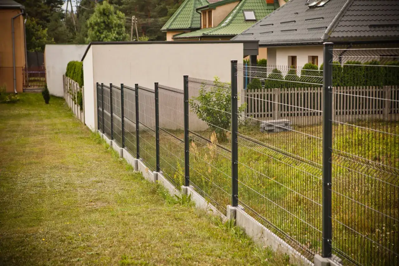 Nowoczesne elementy ogrodzenia panelowego tworzą solidną barierę wokół posesji, oddzielając ją od sąsiednich domów i zieleni.